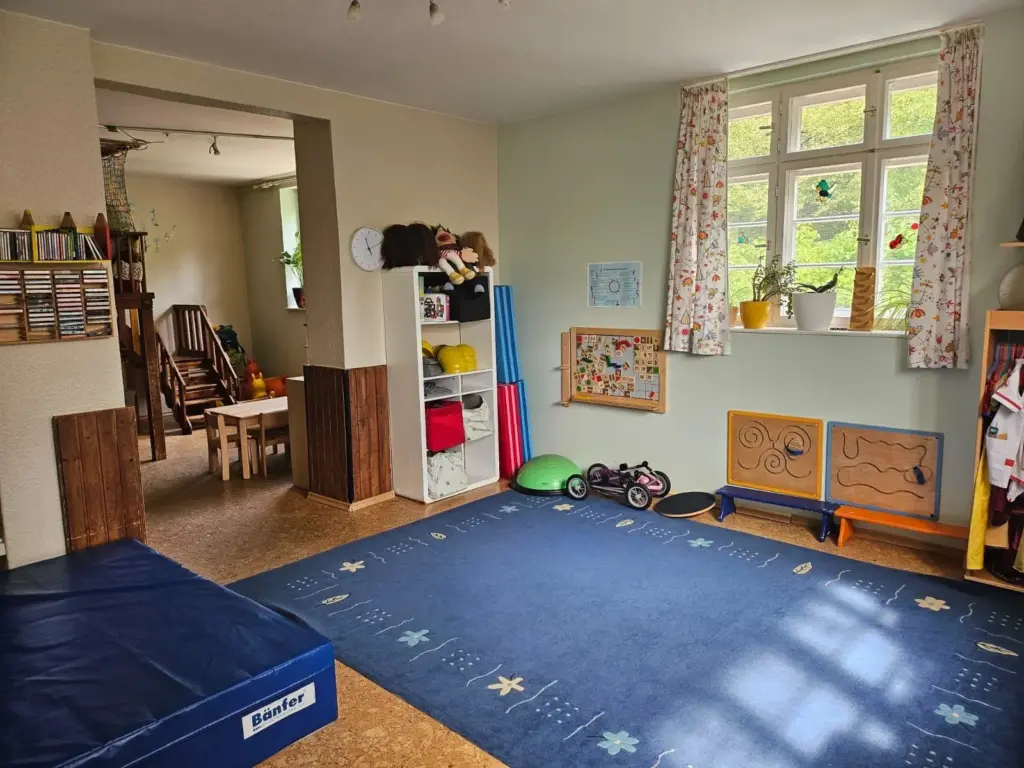 Ein blauer Teppich, daneben eine große blaue Matte. Dahinter ein Durchgang zu einem anderen Zimmer